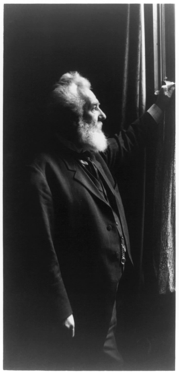 Portrait or photograph of Alexander Graham Bell: Title: Alexander Graham Bell, three-quarter length portrait, standing, facing right, by window Abstract/medium: