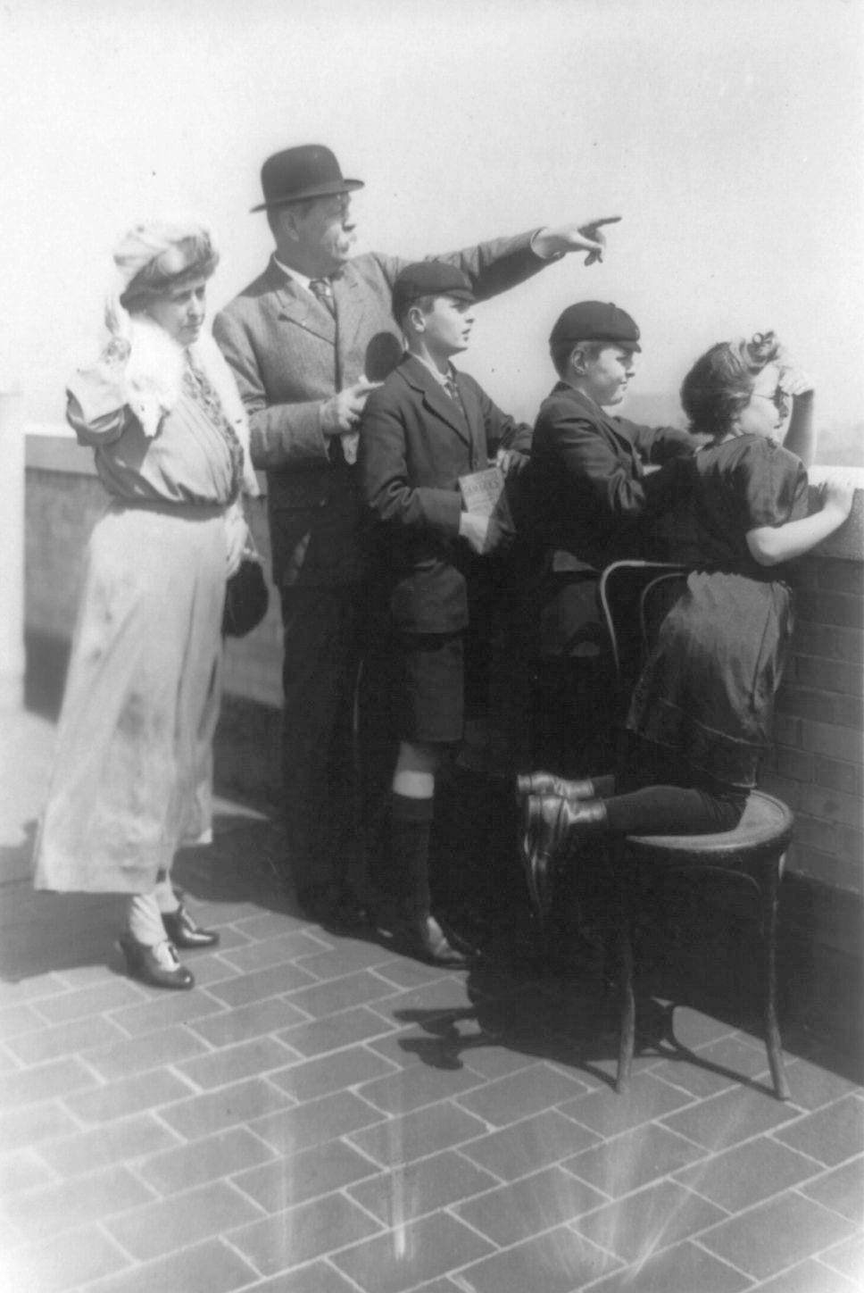 Portrait or photograph of Arthur Conan Doyle: Title: Sir Arthur Conan Doyle and family looking over wall and pointing, New York City Abstract/medium: 1 photogra