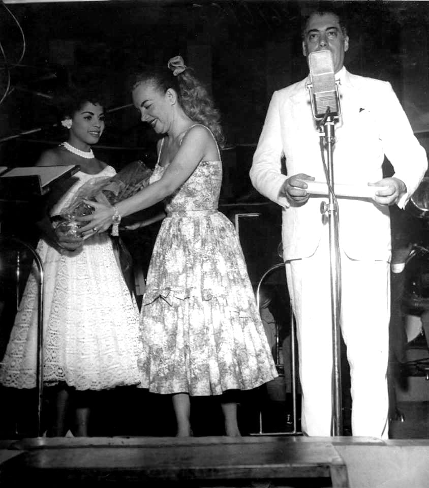 Portrait or photograph of Carmen Miranda: Ângela Maria, Carmen Miranda e Almirante, na Rádio Mayrink Veiga em fevereiro de 1955.