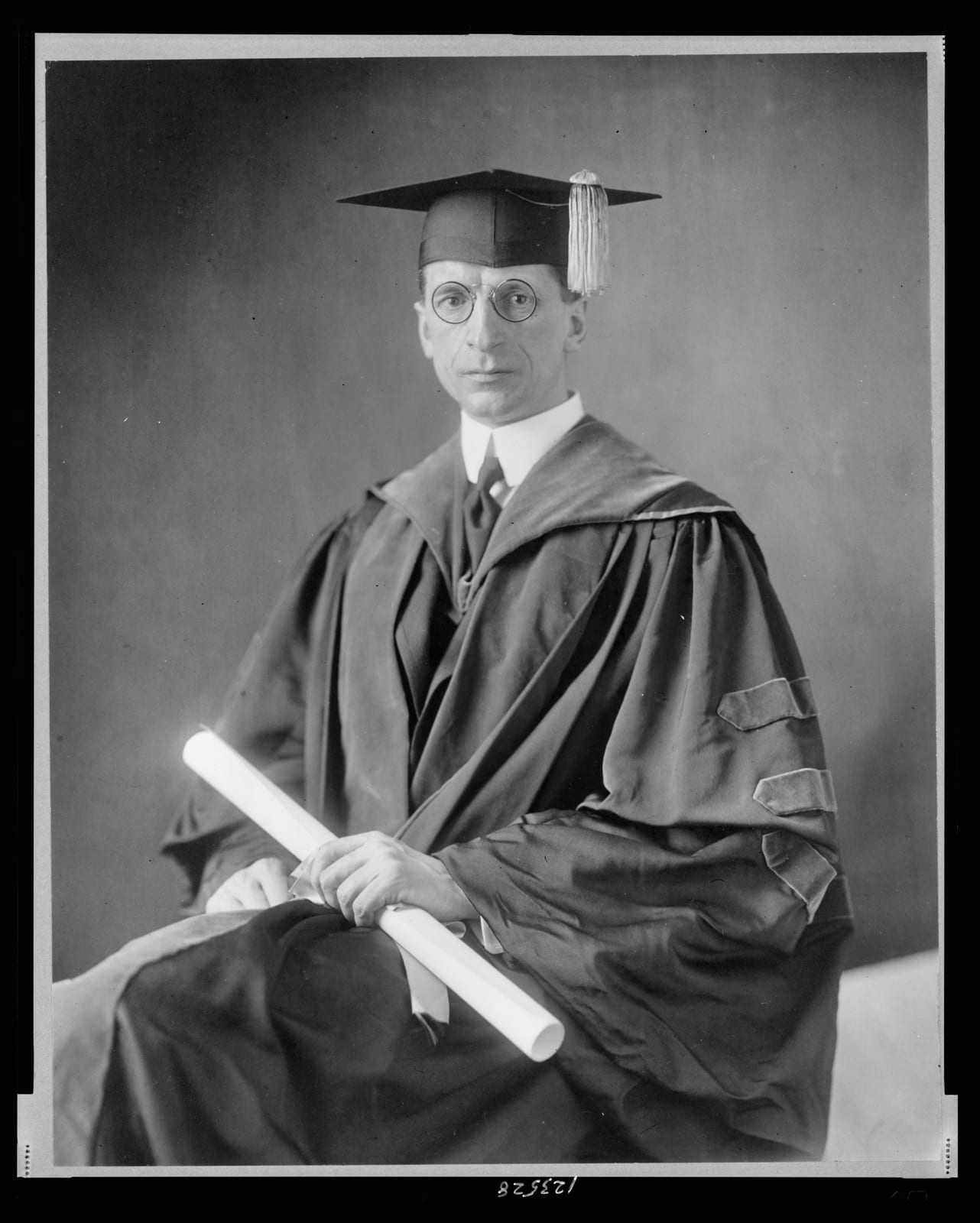 Portrait or photograph of Eamon de Valera: Title: Eamon De Valera, three-quarter length portrait, seated, facing front, wearing cap and gown Abstract/medium: 1