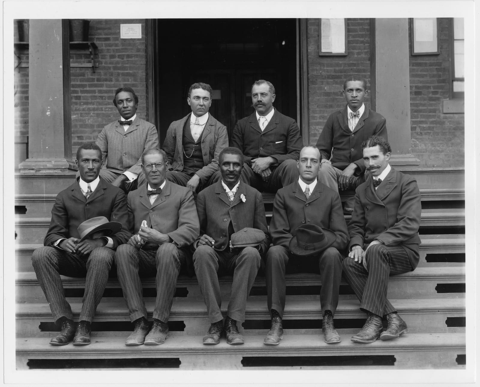 Portrait or photograph of George Washington Carver: Title: George Washington Carver, full-length portrait, seated on steps, facing front, with staff Abstract/me