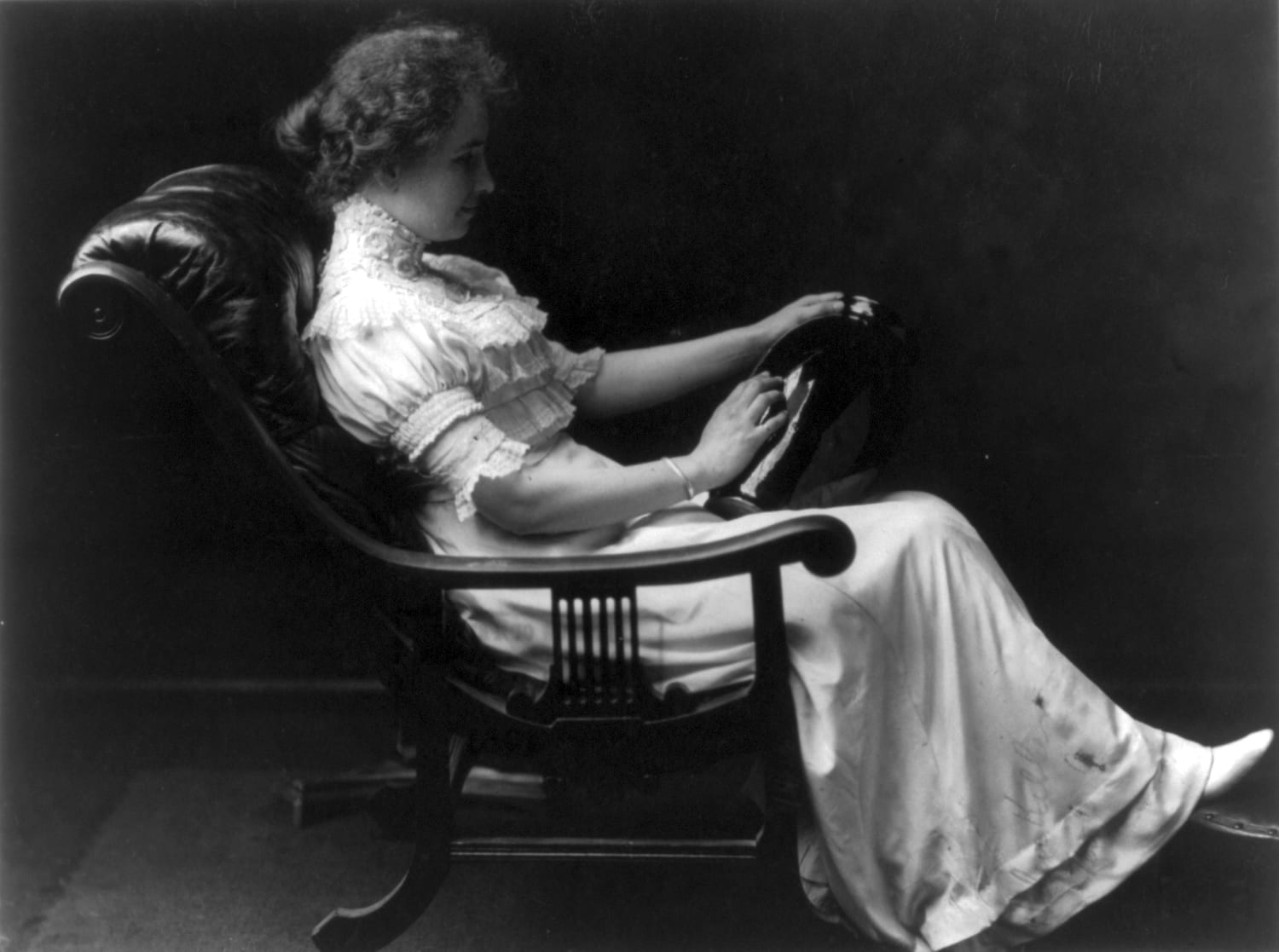Portrait or photograph of Helen Keller: Helen Keller : Portrait, full length, seated, facing right, holding vase in left hand and touching it with right hand.
