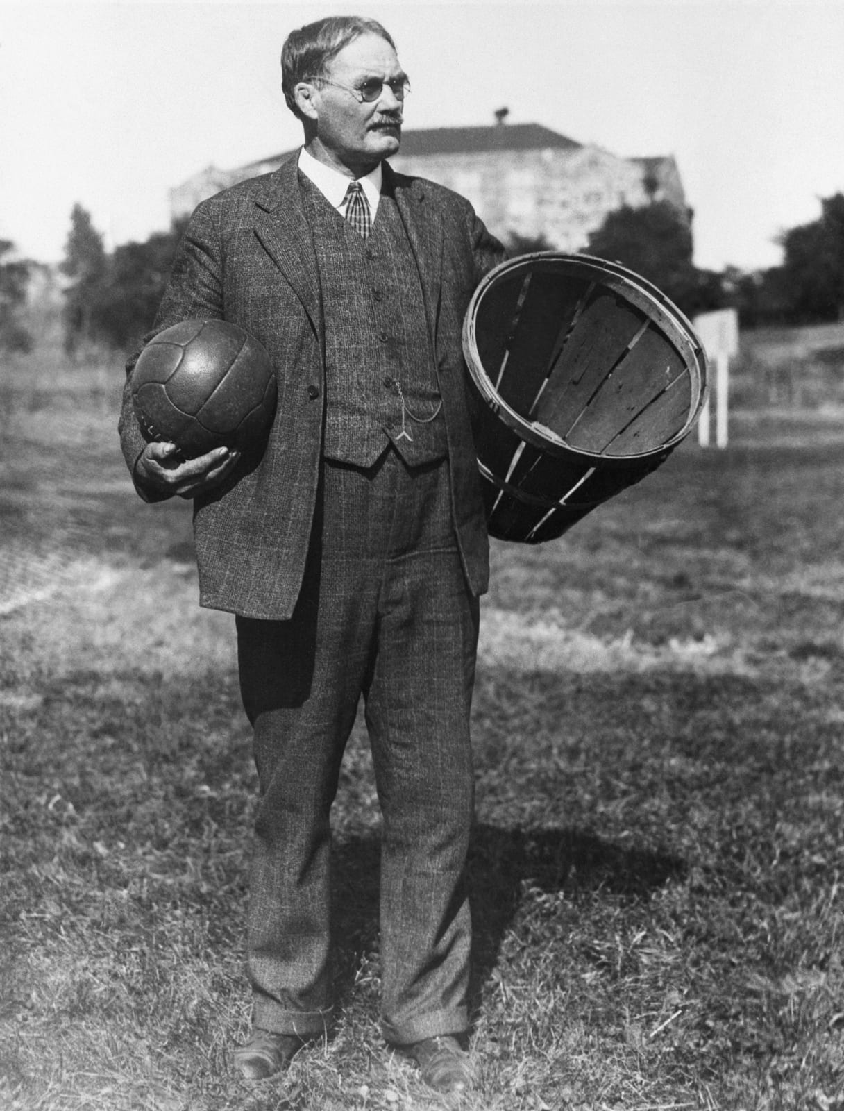 Portrait or photograph of James Naismith: James Naismith with a soccer ball and a basket.