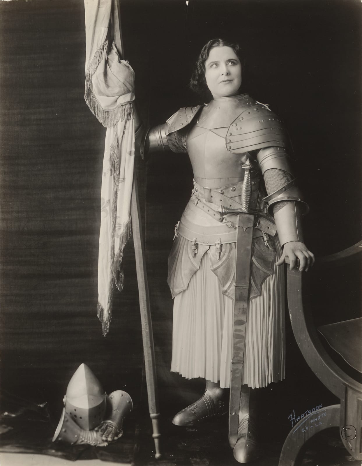 Portrait or photograph of Joan of Arc: Geraldine Farrar, dressed in costume as Joan of Arc, holding a flag.