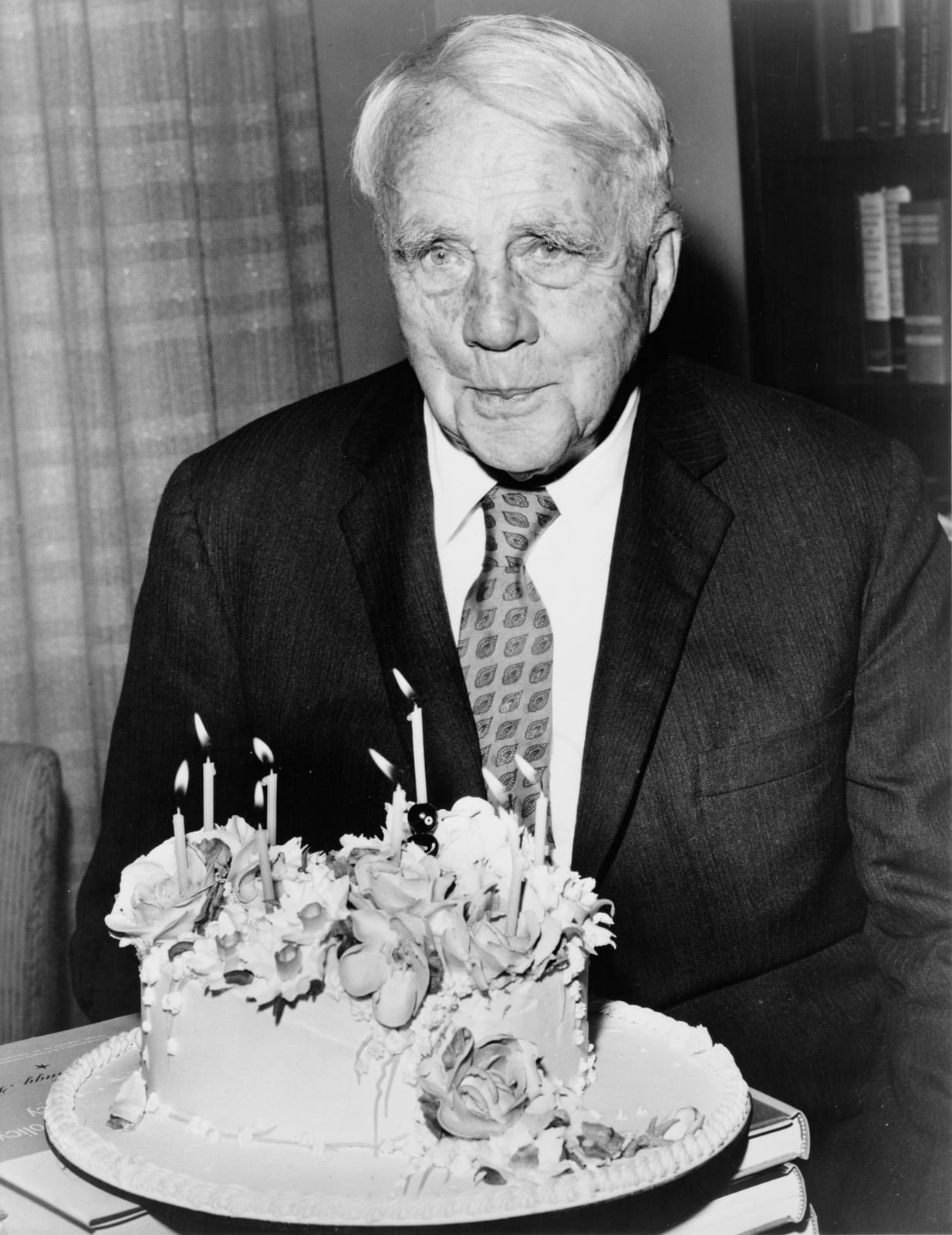 Portrait or photograph of Robert Frost: Robert Frost poses with his birthday cake on his 85th birthday. Waldorf-Astoria hotel in New York City.