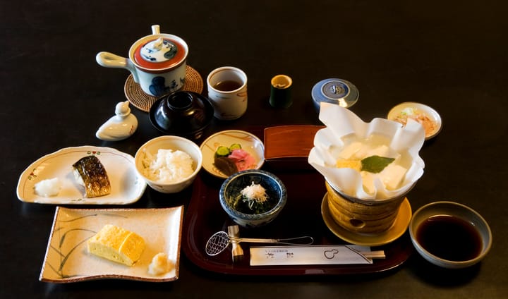 Portrait or photograph of Ryokan: A Traditional breakfast at Tamahan Ryokan, Kyoto. The dishes include roast mackerel, dashimaki (Japanese omelette, here Kansai