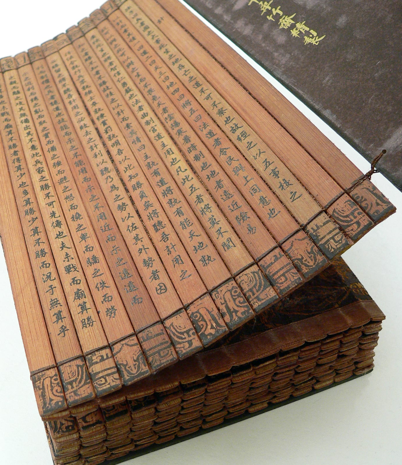 Portrait or photograph of Sun Tzu: A Chinese bamboo book, open to display the binding and contents. This copy of The Art of War (on the cover, "孫子兵法") by Sun Tz