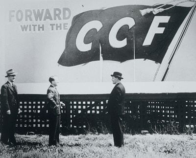 Portrait or photograph of Tommy Douglas: Tommy Douglas standing under a Co-operative Commonwealth Federation billboard with C.M. Fines and Clarence Gillis after
