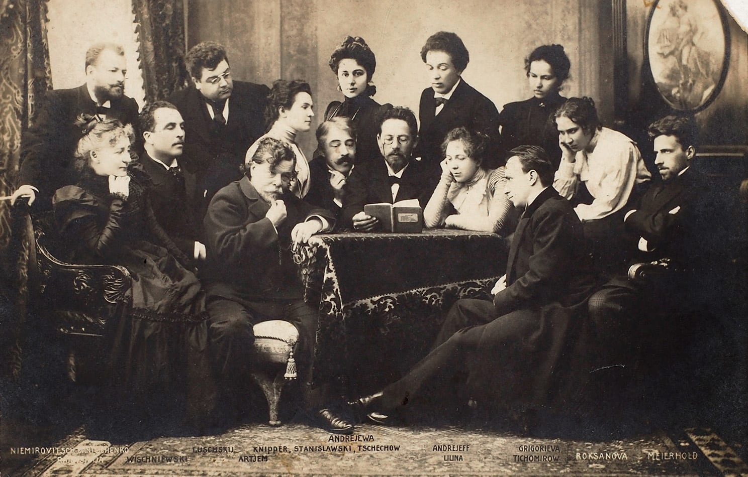 Portrait or photograph of Vsevolod Meyerhold: A posed photograph of Anton Chekhov reading his play The Seagull to the Moscow Art Theatre company. On Chekhov's r