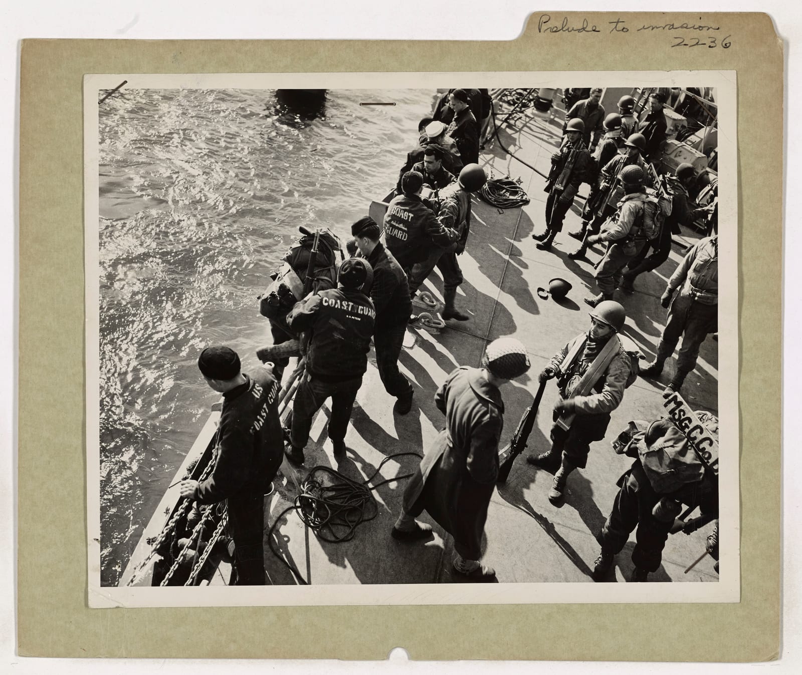 Photograph or image of G.I. Joe: Helmeted and carrying fighting equipment, the American invaders are on their way to practice amphibious landing in preparation